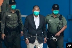 FILE - Correctional officers escort publisher Jimmy Lai to a prison van before a court appearance in Hong Kong on Dec. 12, 2020.