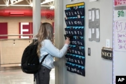 FILE - A ninth-grader places her phone in a holder as she enters class at Delta (Utah) High School, Feb. 23, 2024. Many schools try to regulate student cellphone use, but kids don't always follow the rules and schools enforce them sporadically.